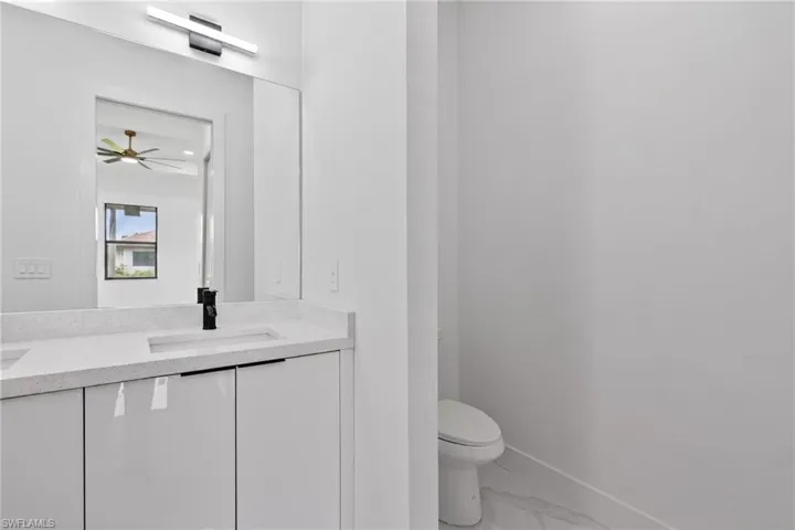 Bathroom vanity featuring a quartz countertop with an integrated rectangular sink, matte black faucet, and white high-gloss cabinetry