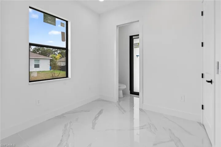 Bright interior featuring a prominent window with black trim, reflecting clear skies