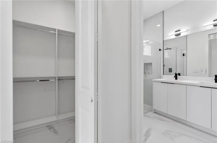 Walk-in closet with chrome hanging rods and white shelving