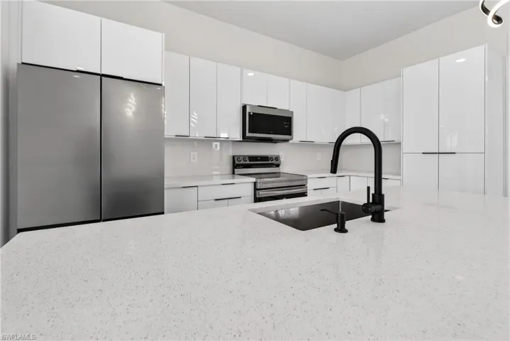 Kitchen featuring a spacious island with an undermount sink and matte black gooseneck faucet
