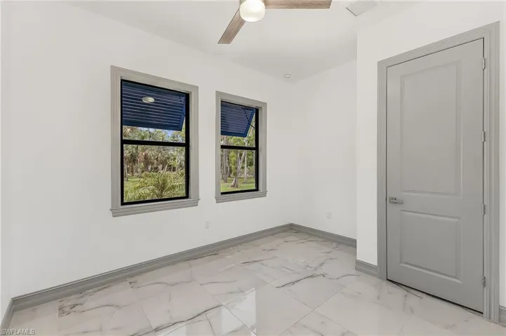 Tiled spare room featuring ceiling fan
