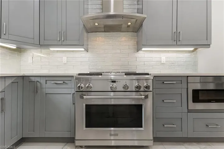 Kitchen featuring wall chimney range hood, backsplash, and appliances with stainless steel finishes