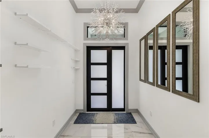 Tiled foyer entrance featuring a chandelier and ornamental molding
