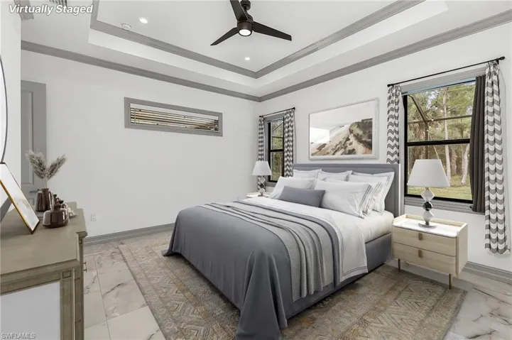 Bedroom featuring ceiling fan, tile patterned floors, crown molding, and a tray ceiling