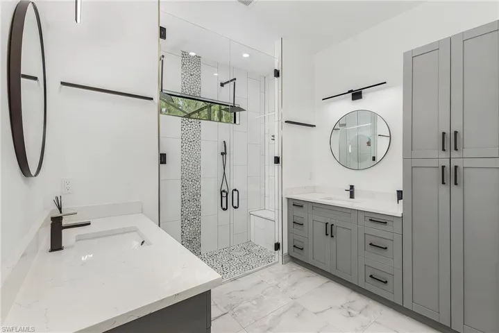 Bathroom featuring tile floors, an enclosed shower, and double vanity
