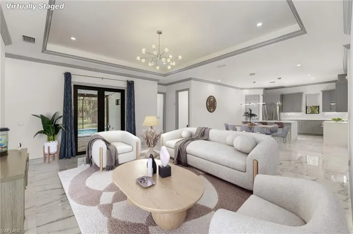 Tiled living room with a chandelier, ornamental molding, and a raised ceiling
