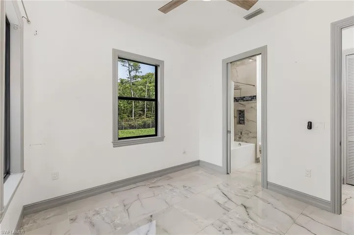 Tiled spare room featuring ceiling fan