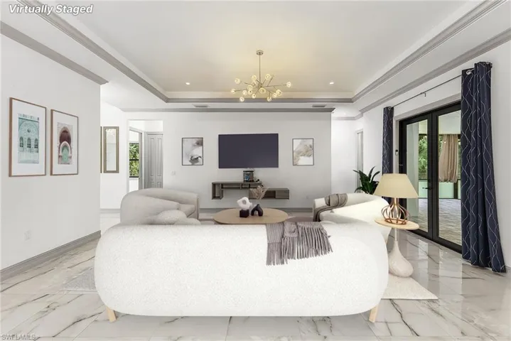 Tiled living room with a tray ceiling, french doors, and an inviting chandelier