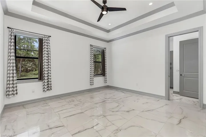 Empty room featuring ceiling fan, ornamental molding, and a tray ceiling