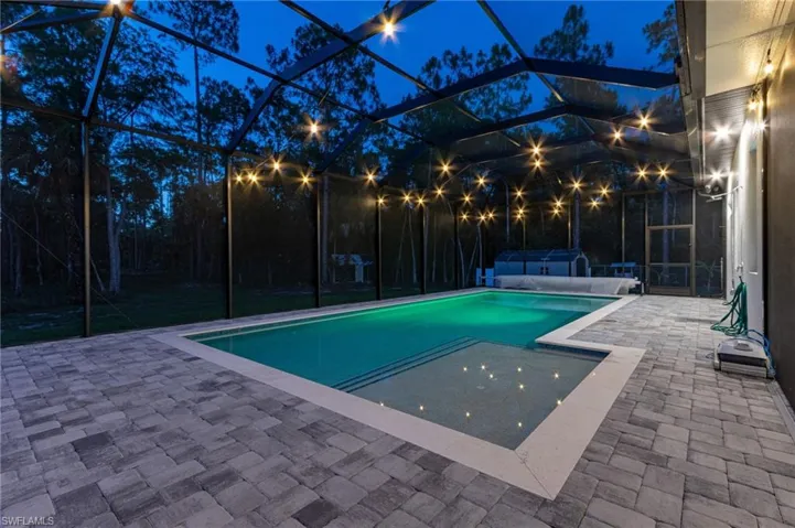 Pool at twilight featuring a lanai and a patio