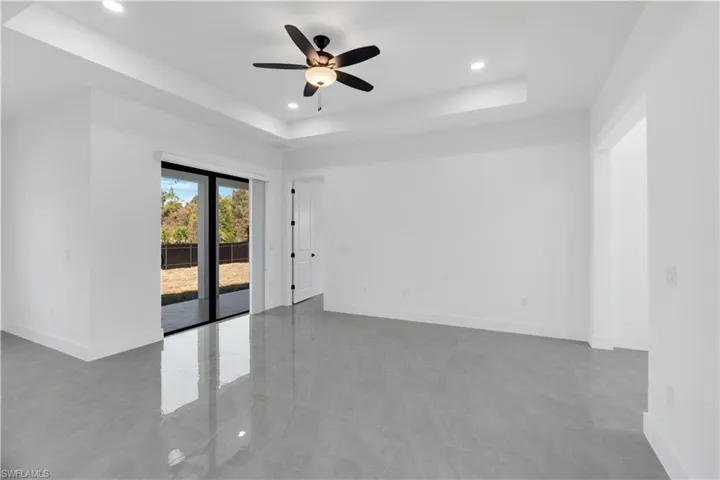 Spare room with a ceiling fan, a raised ceiling, and recessed lighting