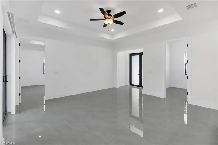 Empty room with a ceiling fan, recessed lighting, french doors, light tile patterned flooring, and a raised ceiling