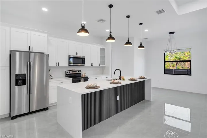 Kitchen featuring stainless steel appliances, glass fronted cabinets, pendant lighting, and white cabinets