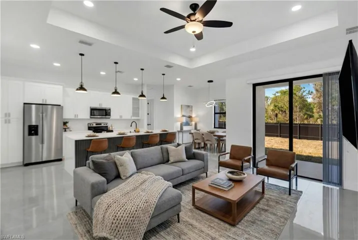Living room featuring ceiling fan, recessed lighting, and a high tray ceiling