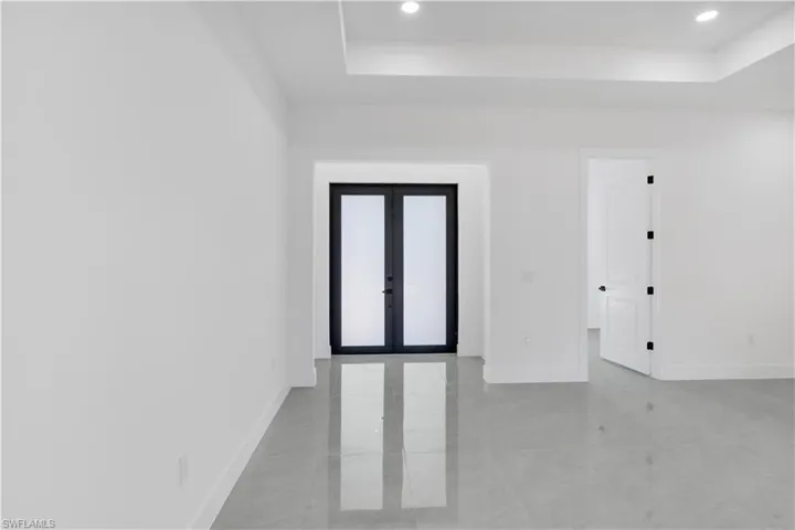 Empty room featuring french doors, recessed lighting, and a raised ceiling