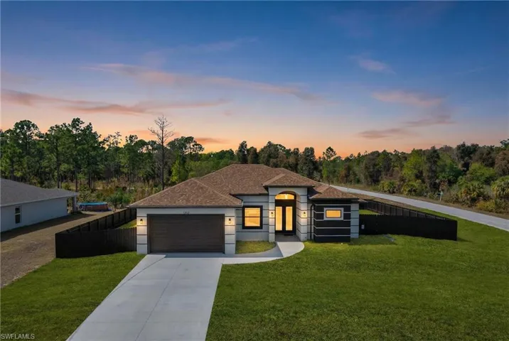 View of front facade featuring driveway, an attached garage, a shingled roof, and stucco siding