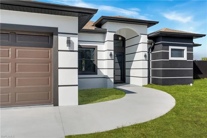 View of front of property with stucco siding, a garage, and a front lawn