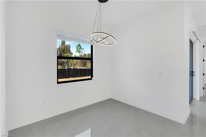 Unfurnished room with baseboards and a chandelier