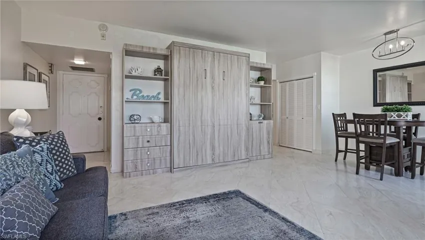 Tiled living room featuring built in shelves and a chandelier