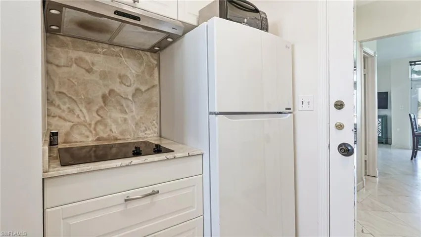 Kitchen featuring white cabinets, black electric stovetop, and light tile patterned floors