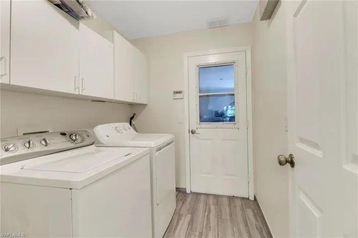 Laundry room featuring white cabinetry, a white washer and dryer, and wood-look tile flooring
