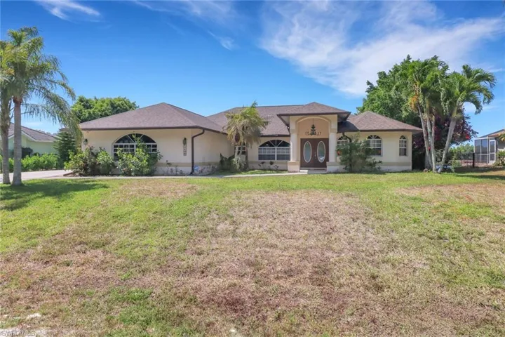 The property features a stucco exterior, an arched entryway, and a brown double door with glass inserts