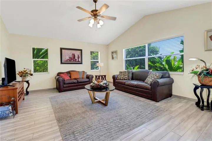The living room features vaulted ceilings, tile flooring, and several windows providing natural light