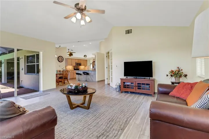 Living area featuring vaulted ceilings, light-toned flooring, and glass sliding doors
