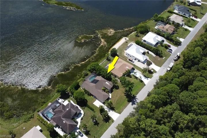 Aerial view of the property, showcasing its location along a body of water and a paved road