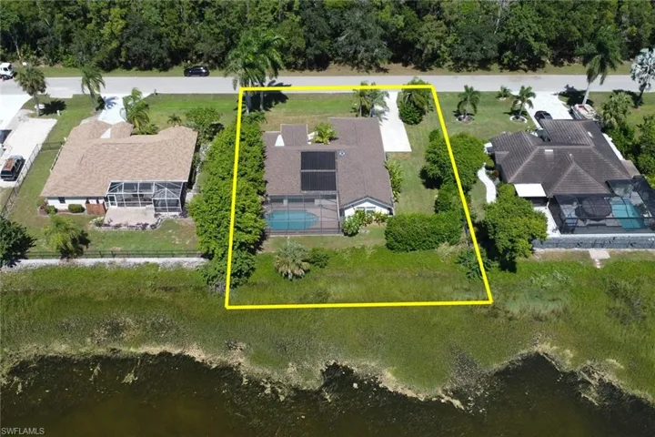 An aerial view showcasing the property with a private pool, a screened enclosure, and a well-maintained lawn
