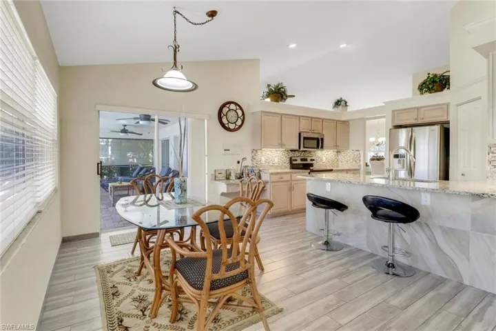 The dining area features light-colored flooring, a glass-top table, and an ornate hanging light fixture