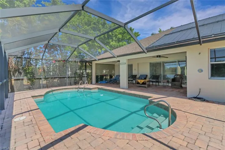 The property features an outdoor swimming pool with a screened enclosure, surrounded by brick pavers