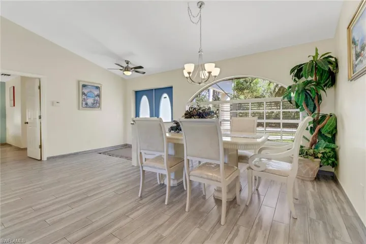 The dining area features light-colored flooring, a vaulted ceiling, and an arched window providing natural light