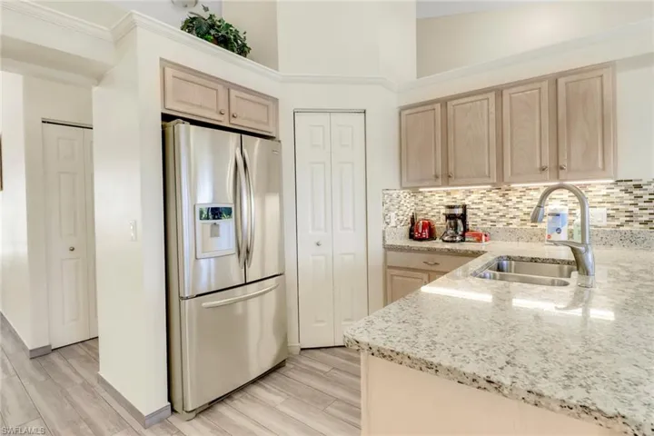 The kitchen features light-toned cabinetry, stainless steel appliances, and granite countertops