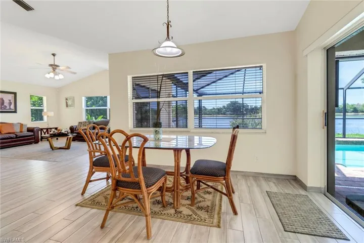 Spacious dining area with light-toned flooring, an elegant overhead light fixture, and large windows offering views of the water