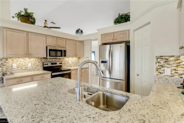 The kitchen features granite countertops, a stainless steel refrigerator, and a stainless steel oven and microwave