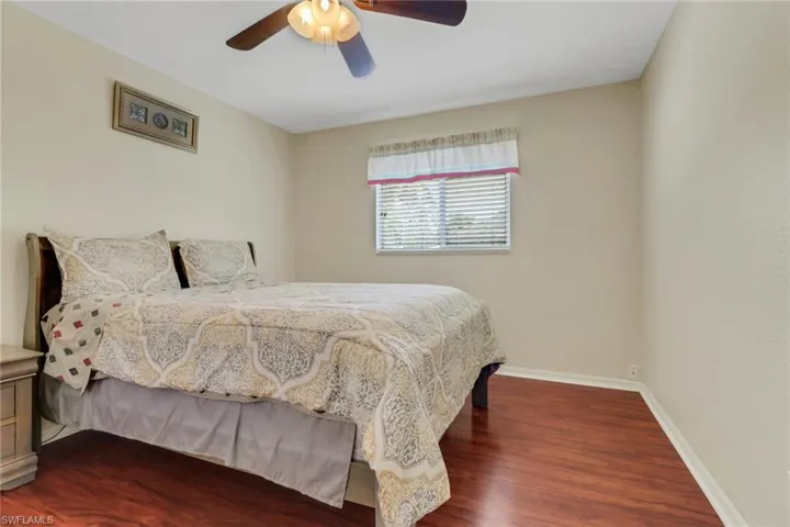The room features rich wood flooring and a ceiling fan for comfort