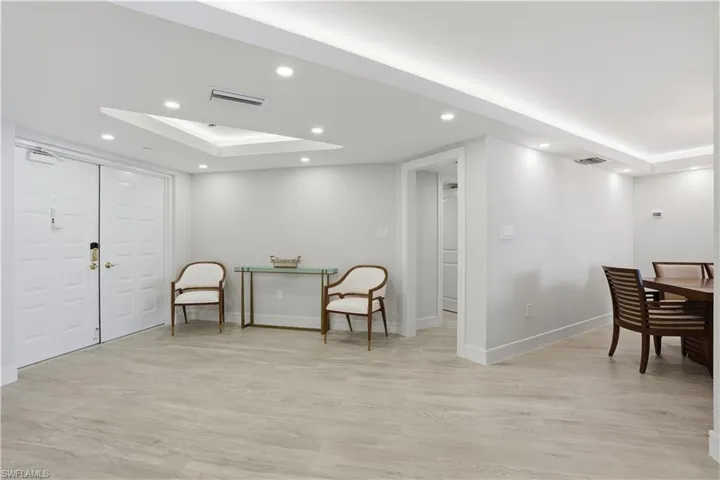 Interior space featuring wood-finish flooring, recessed lighting, recessed ceiling tray design with integrated cove lighting, and double-door entry