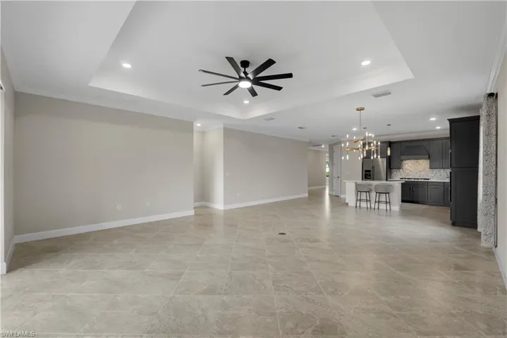 Expansive tiled flooring complemented by a tray ceiling with recessed lighting and a ceiling fan