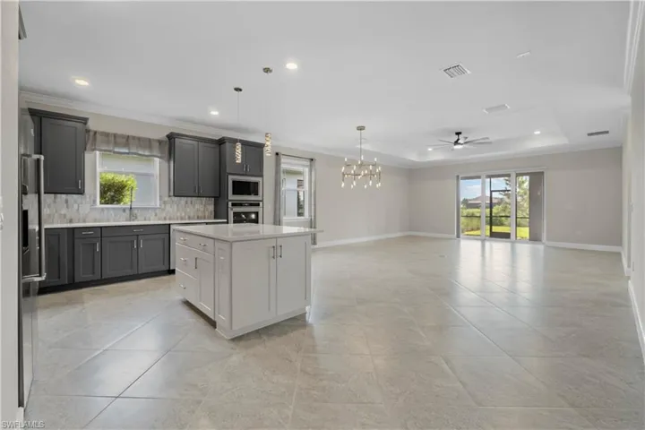 Open-concept kitchen and living area featuring a central island, recessed lighting, and a tray ceiling