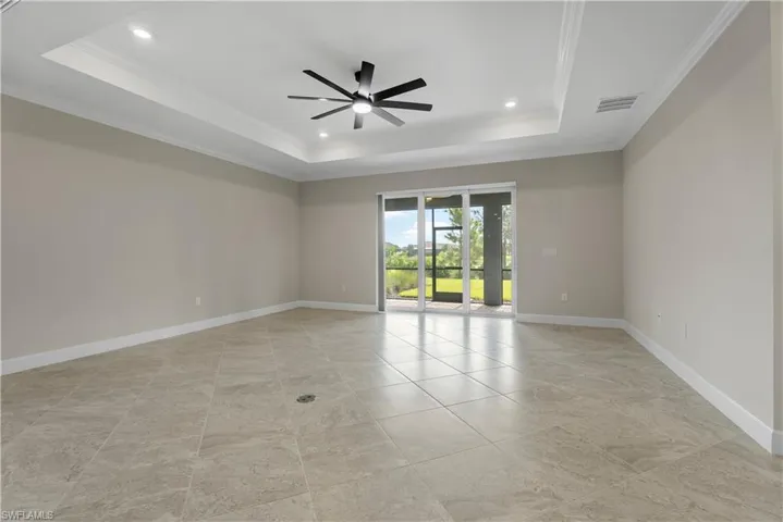 Tray ceiling with recessed lighting and a ceiling fan, tiled flooring, and sliding glass doors to an outdoor screened area