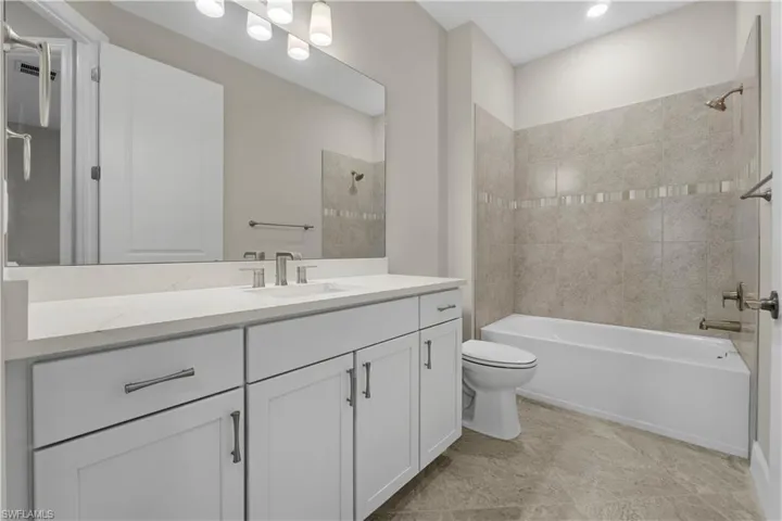 White vanity with brushed nickel hardware, light-toned countertop, rectangular undermount sink, and full-width mirror