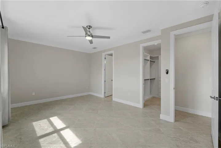 Spacious room featuring tile flooring, a modern ceiling fan, and access to a built-in closet system