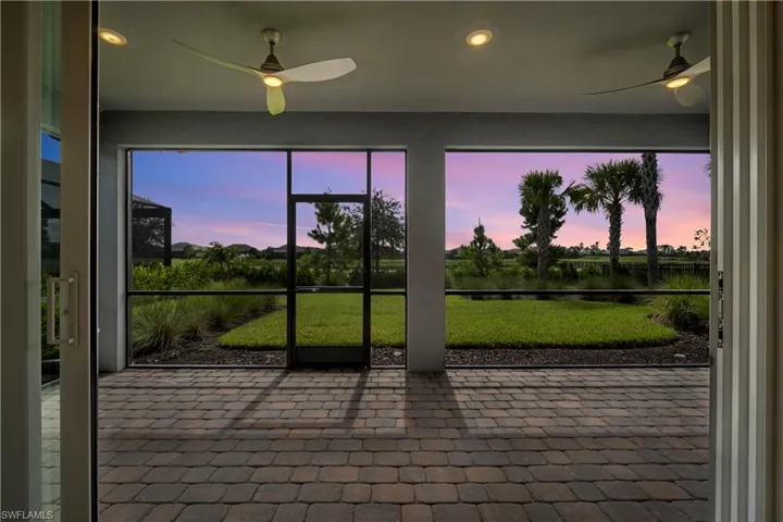 Screened-in patio featuring paver flooring, recessed lighting, and dual ceiling fans