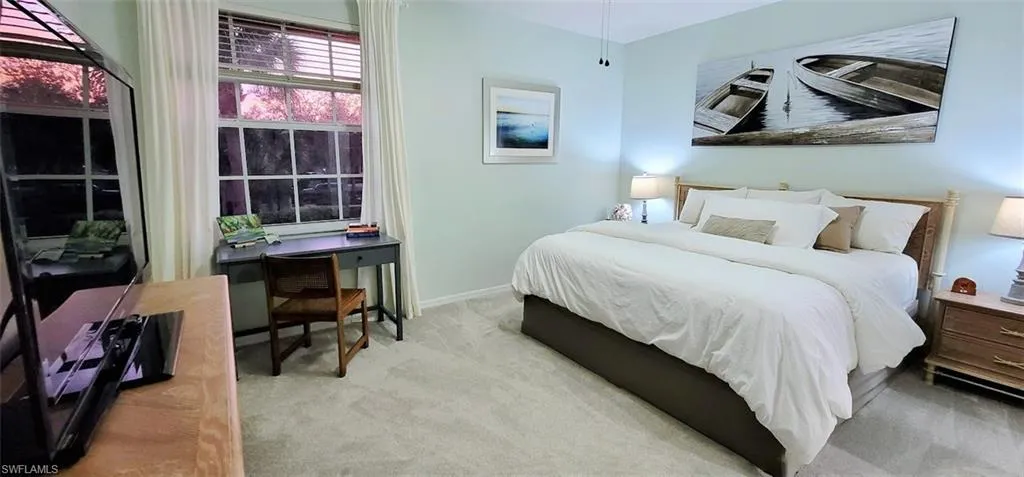 King bed in guest bedroom with TV and desk