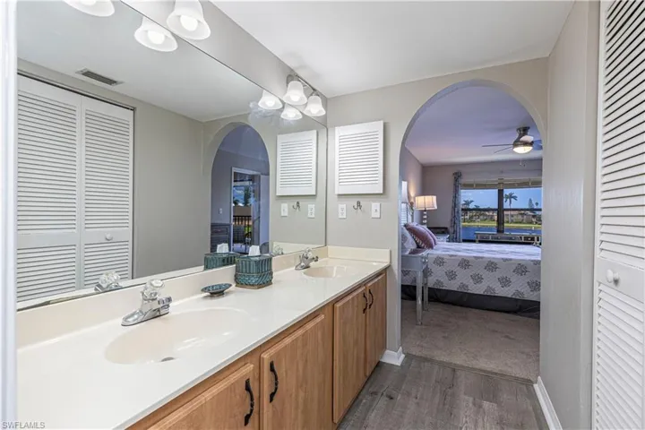 Primary suite bathroom featuring a walk in closet, connected bathroom, double vanity