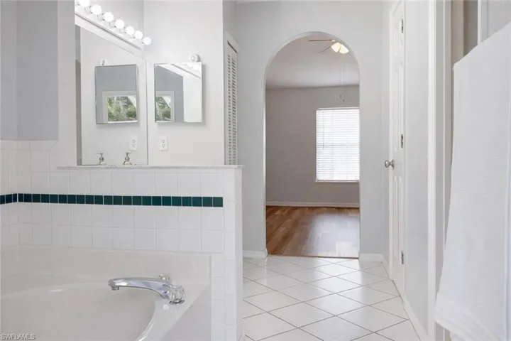 Full bathroom with light tile patterned floors, a bath, and ceiling fan