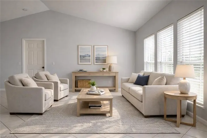 Living room with vaulted ceiling, healthy amount of natural light, and light tile patterned flooring