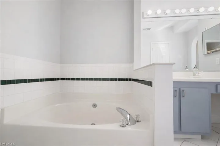 Full bath with a bath, light tile patterned flooring, and vanity
