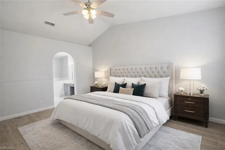 Master_Bedroom featuring vaulted ceiling, light wood-style flooring, ensuite bathroom, ceiling fan, and arched walkways
